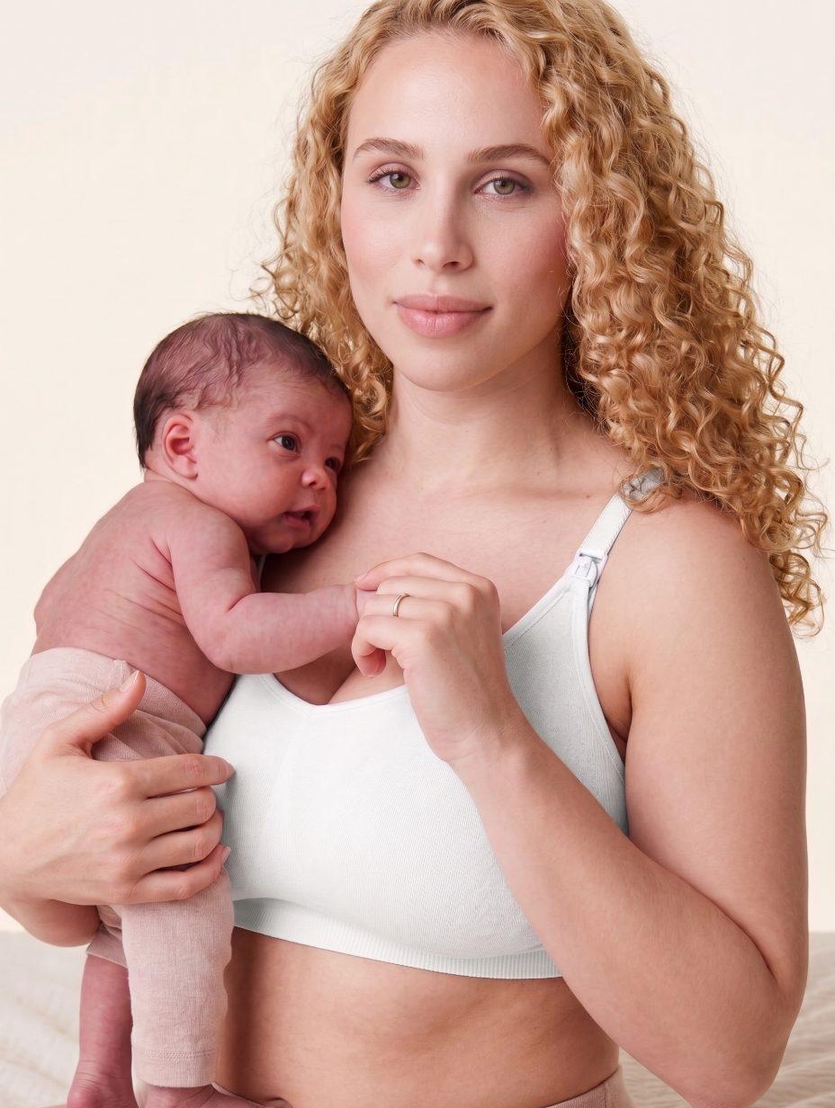 A mother holding her newborn, wearing The Yael